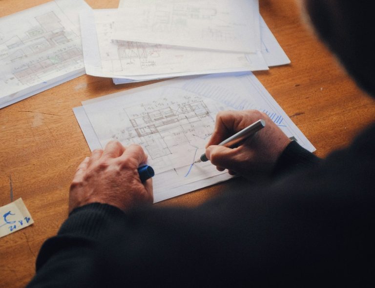 Arbeit an Architekturzeichnungen am Schreibtisch – Symbolfoto zum Beratungsablauf